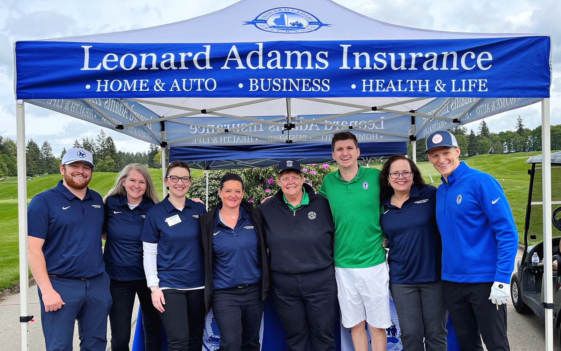 Careers - Leonard Adams Insurance Team Standing and Smiling Under a Canopy with Their Agency Name While Posing for a Photo